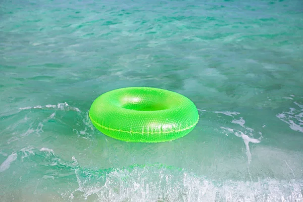 floating ring on sandy beach with waves reflecting in summer sun