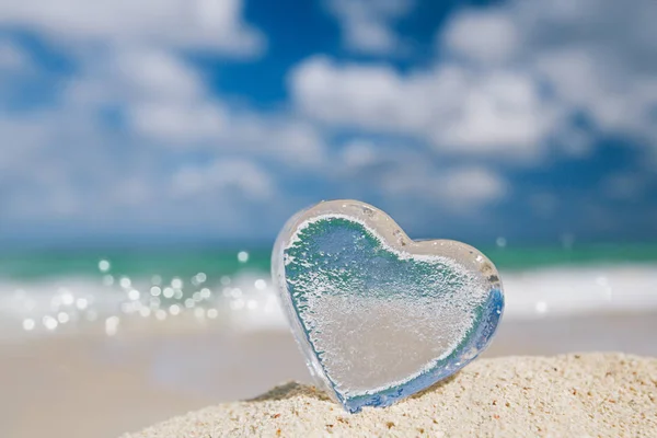 Clear glass heart on white sand beach, — Stock Photo, Image