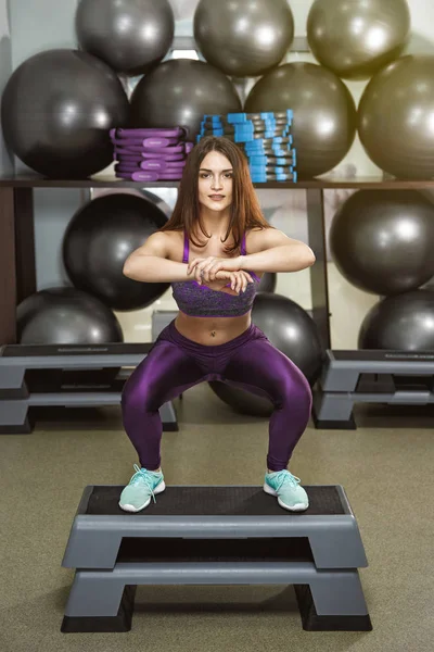 Sports girl trains and exercises in the gym.