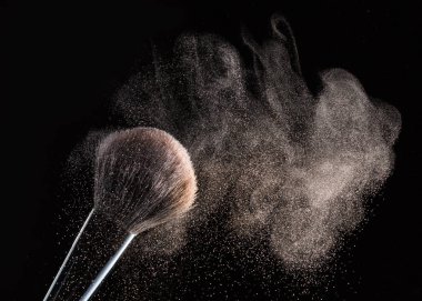 Siyah bir arka plan üzerinde toz uçan ile makyaj için fırça izole.