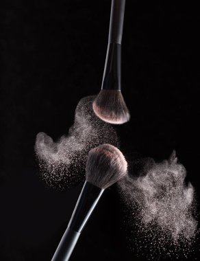 Siyah bir arka plan üzerinde toz uçan ile makyaj için fırça izole.