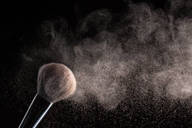 Siyah bir arka plan üzerinde toz uçan ile makyaj için fırça izole.