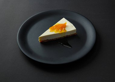 İzole bir siyah arka plan üzerine siyah bir plaka üzerinde reçelli cheesecake tatlı.