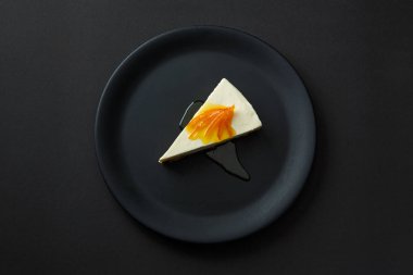İzole bir siyah arka plan üzerine siyah bir plaka üzerinde reçelli cheesecake tatlı.