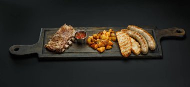 Sosis ile Yönetim Kurulu; Pirzola, patates ve sosu bir siyah arka plan üzerine izole bira için.