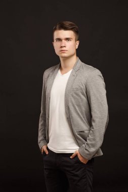 bir ceket ve siyah bir arka plan üzerinde bir T-shirt genç bir adam portresi.