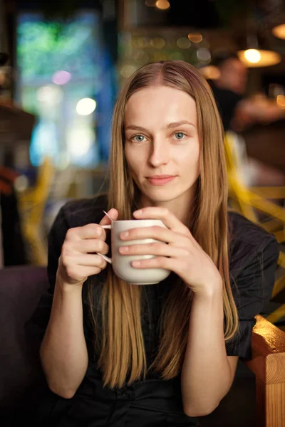 young woman with a cup of tea sitting in a cafe.