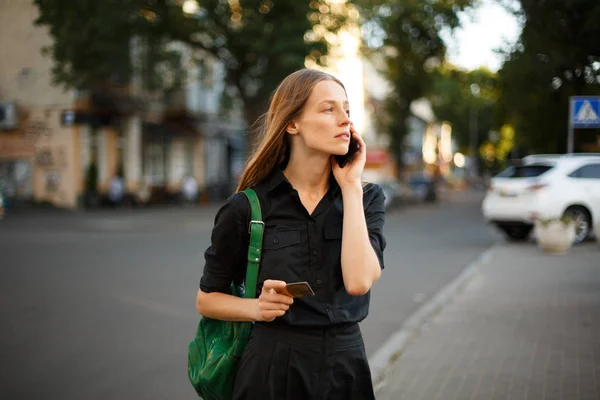 young woman with credit card and smartphone in hand on the background of old city street