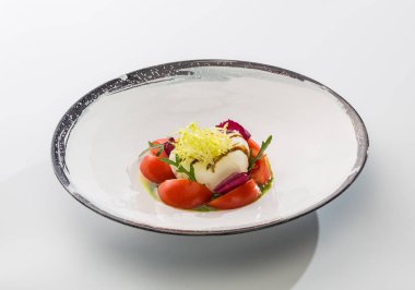 Domates ve beyaz arka plan üzerinde izole bir plaka üzerinde yağda otlar peynir mozzarella.