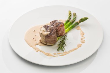 şiş kebap sosu ve beyaz arka plan üzerinde izole bir plaka üzerinde kuşkonmaz ile iki adet.