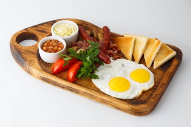 Sahanda yumurta ve beyaz arka plan üzerinde izole bir ahşap tahta üzerinde ızgara sosis kahvaltı.