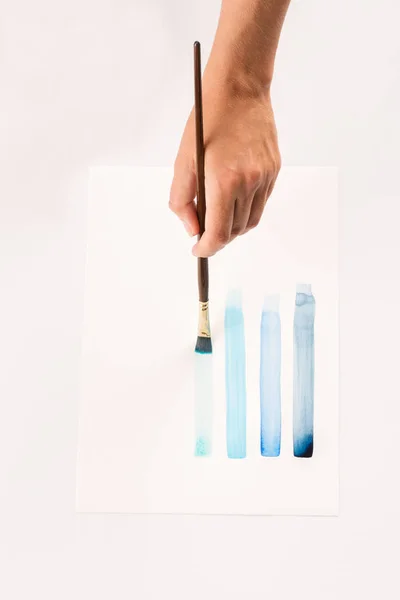 Mão com uma escova desenha no fundo do papel branco — Fotografia de Stock