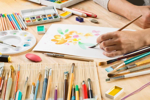 bir fırça ile el bir beyaz kağıt arka planda brushe arasında çizer