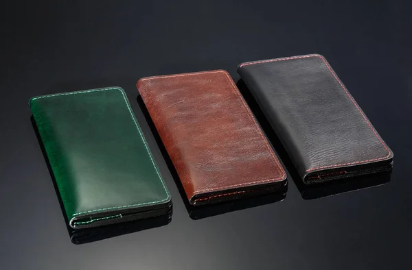 Três carteira de couro em um fundo preto — Fotografia de Stock