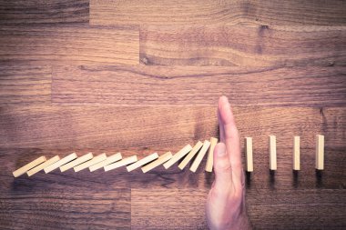 Risk yönetimi konsepti. Risk Yöneticisi (veya başka bir iş adamı) sorunlu çözüme sahiptir. İşadamı domino etkisini durdurdu, üst görünüm.
