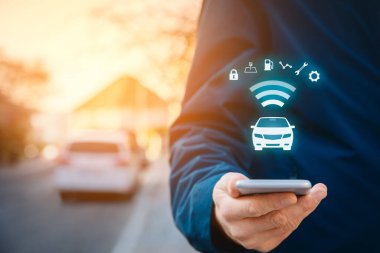Akıllı telefon konsepti, akıllı araç konsepti ve akıllı araba konsepti üzerine akıllı araba uygulaması. Sokakta akıllı telefonu olan biri, arka planda arabası ve arabayla kablosuz iletişimi olan biri..