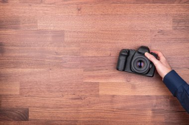 Profesyonel fotoğrafçı fotoğraf çekimi için hazırlanıyor ve tahta masadan DSLR fotoğraf makinesini alıyor. Fotoğraf tasarım ögesi arkaplan için ideal.