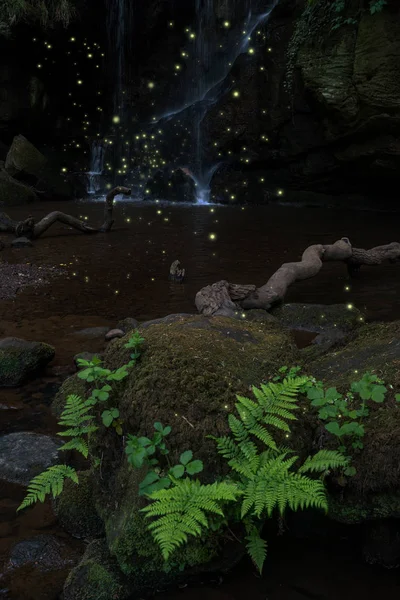 Stunning waterfall landscape at dusk with fireflies glowing around foliage