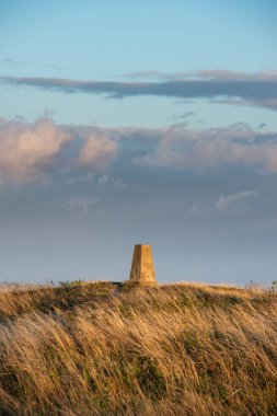 İngiliz kırsalındaki South Downs Ulusal Parkı 'ndaki trigonometri noktasının güzel yaz günbatımı manzarası