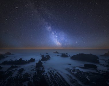 Stunning vibrant Milky Way composite image over landscape of long exposure seascape clipart