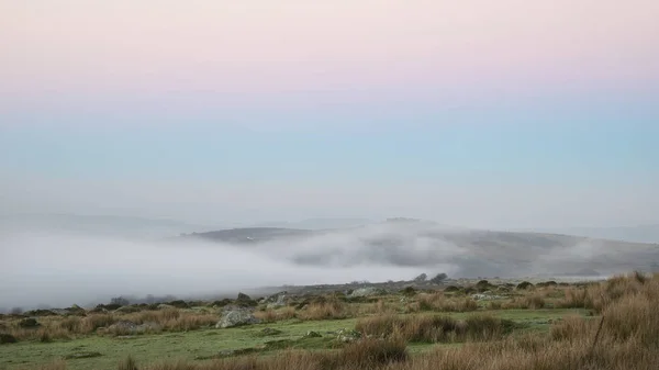 霧を通してダートムーア明らかピークに Tor 経由霧日の出風景を見事な — ストック写真