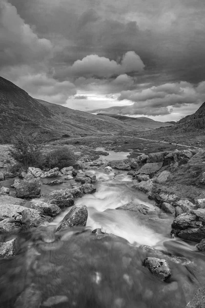Black and white Landscape image of river flowing down mountain range near Llyn Ogwen and Llyn Idwal in Snowdonia in Autumn