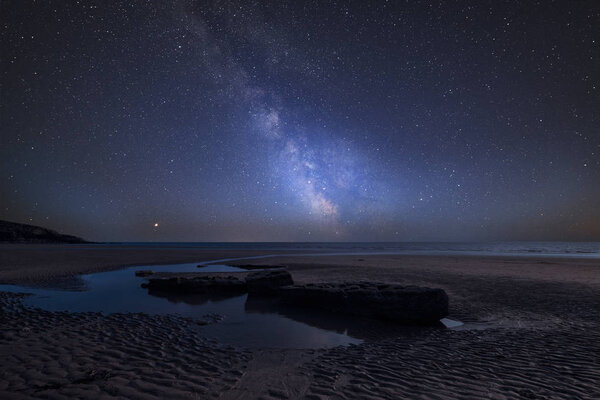 Stunning vibrant Milky Way composite image over landscape of Dunraven Bay in Wales