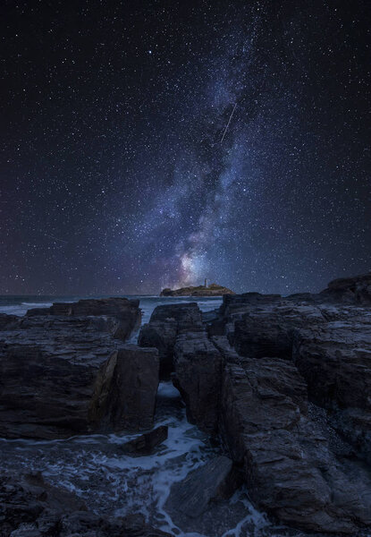 Stunning vibrant Milky Way composite image over landscape of Godrevy lighthouse on Cornwall coastline in England