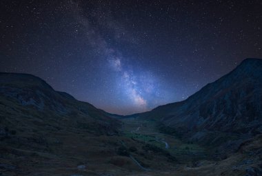 Stunning vibrant Milky Way composite image over Beautiful moody landscape image of Nant Francon valley in Snowdonia clipart