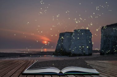 Güzel renkli sunset beach yatay, açık hikaye kitabın sayfalarını dışarı geliyor bir fantezi stil görüntüde parlayan ateş böcekleri üzerinde kaya yığınları üzerinde