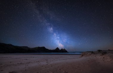Stunning vibrant Milky Way composite image over landscape of yellow sandy beach Three Cliffs bay clipart