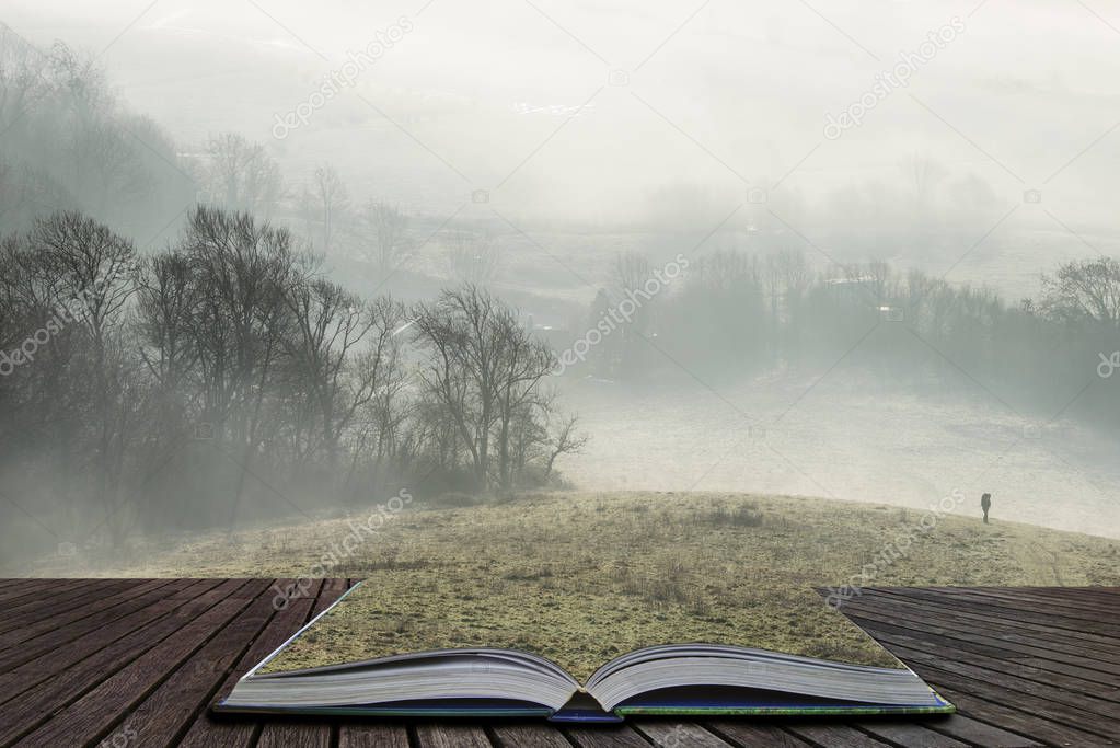 Beautiful foggy English countryside landscape at sunrise in Winter with layers rolling through the fields coming out of pages in magical story book