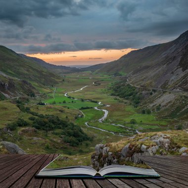 Beautiful moody landscape image of Nant Francon valley in Snowdonia during sunset in Autumn coming out of pages of open story book clipart