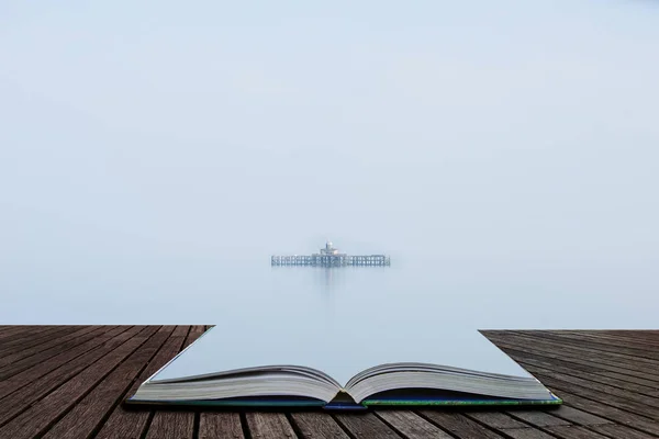 開いた本のページから出てくる浮遊遺跡の外観を与える霧の朝の中に海のまま遺棄桟橋のファインアート ミニマルな風景画像 — ストック写真