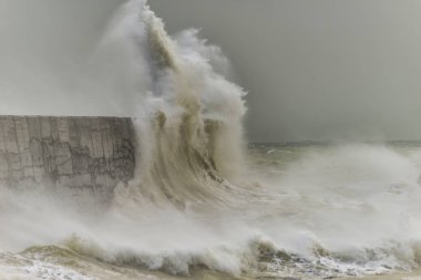 Stunning waves crashing over harbor wall during windy storm at Newhaven on English coast clipart