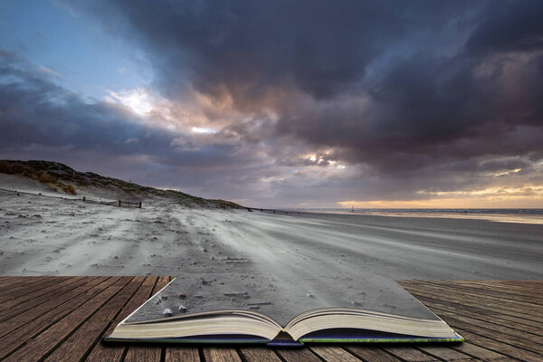 Beautiful Winter sunrise over West Wittering beach in Sussex England with wind blowing sand across the beach in pages of open book, story telling concept