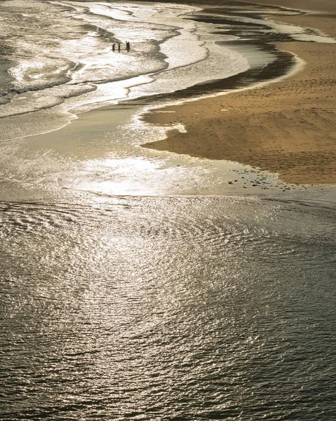 Persone non identificate che giocano e pescano nell'oceano a Three Cliffs — Foto Stock