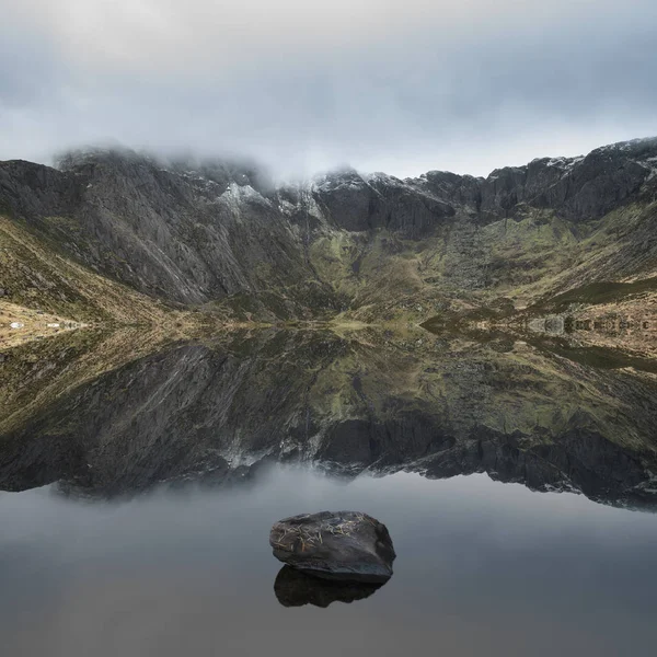 Beautiful moody Winter landscape image of Llyn Idwal and snowcap — Stock Photo, Image