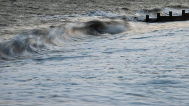 Gün batımında Groynes 'e çarpan dalgaların soyut ve güzel manzarası.