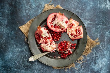 Yırtık Nar meyvesi ve tohumlarının düz görünümü pürüzlü arka planda yatıyordu