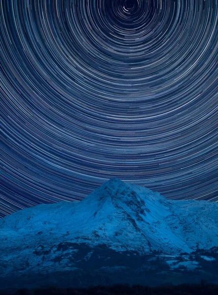 Digital composite image of star trails around Polaris with Stunning vibrant landscape of Mount Snowdon