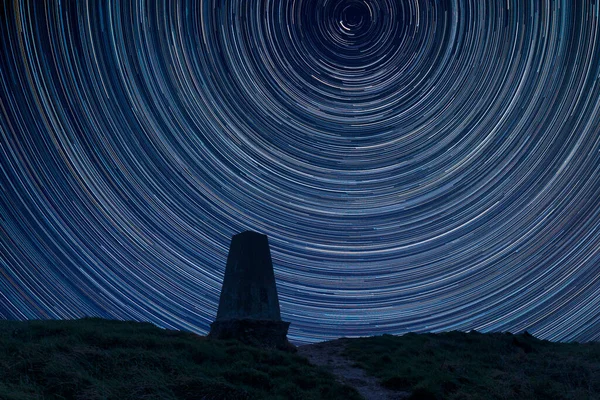 Digital composite image of star trails around Polaris with Beautiful Autumn Fall landscape of South Downs National Park in English countryside