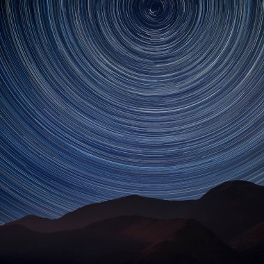 Polaris 'in etrafındaki yıldız izlerinin dijital bileşik görüntüsü ve Lake District bölgesindeki dağ tarafının çarpıcı manzarası. 