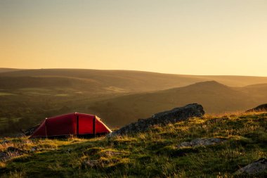 Göz kamaştırıcı yaz gündoğumu sırasında güneşin sıcacık parlaklığıyla İngiliz kırsalındaki vahşi kampın güzel görüntüsü manzarayı aydınlatıyor.