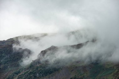 İngiliz Göl Bölgesi 'ndeki dağ zirvelerinin güzel manzarası yaz sabahının sonlarına doğru dağların tepelerinde alçak bulutlar asılı.