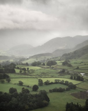 Derwentwater Vadisi boyunca uzanan güzel manzara. Dağların arasından süzülen yağmur, aşağıdaki yemyeşil kırsal alana düşüyor.