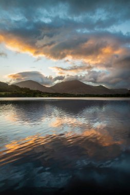 Göz kamaştırıcı gündoğumu manzarası. Göl Bölgesi 'ndeki Loweswater' dan Alçak Fell ve Grasmere 'e doğru bakıyor. Dağların zirvelerinde renkli gökyüzü kırılıyor.
