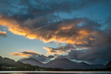 Göz kamaştırıcı gündoğumu manzarası. Göl Bölgesi 'ndeki Loweswater' dan Alçak Fell ve Grasmere 'e doğru bakıyor. Dağların zirvelerinde renkli gökyüzü kırılıyor.