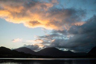 Göz kamaştırıcı gündoğumu manzarası. Göl Bölgesi 'ndeki Loweswater' dan Alçak Fell ve Grasmere 'e doğru bakıyor. Dağların zirvelerinde renkli gökyüzü kırılıyor.