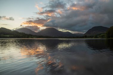 Göz kamaştırıcı gündoğumu manzarası. Göl Bölgesi 'ndeki Loweswater' dan Alçak Fell ve Grasmere 'e doğru bakıyor. Dağların zirvelerinde renkli gökyüzü kırılıyor.